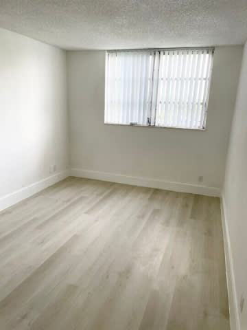 A room with a window and wooden flooring.
