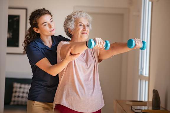 a woman holding two dumbbells while standing next to an older woman