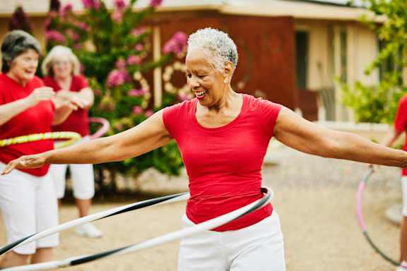 a group of older women exercise with hula hoops