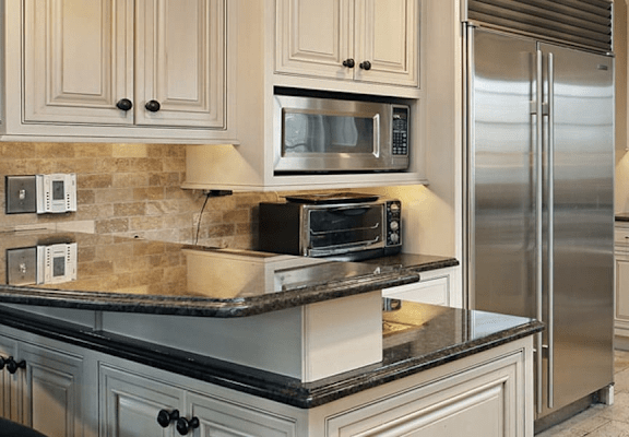 A kitchen with a black countertop and stainless steel appliances.