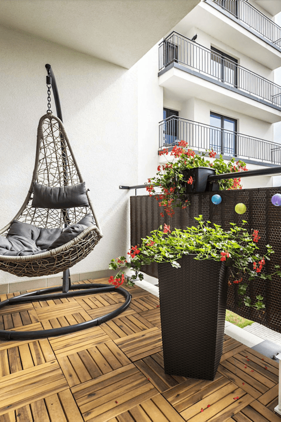 A black hanging chair is on a wooden deck.