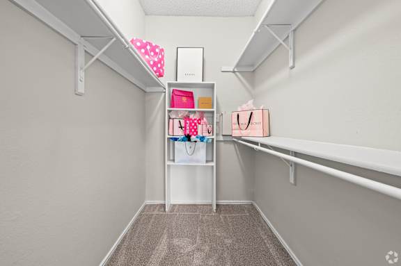 A white shelf with a pink bag and a white box on it.