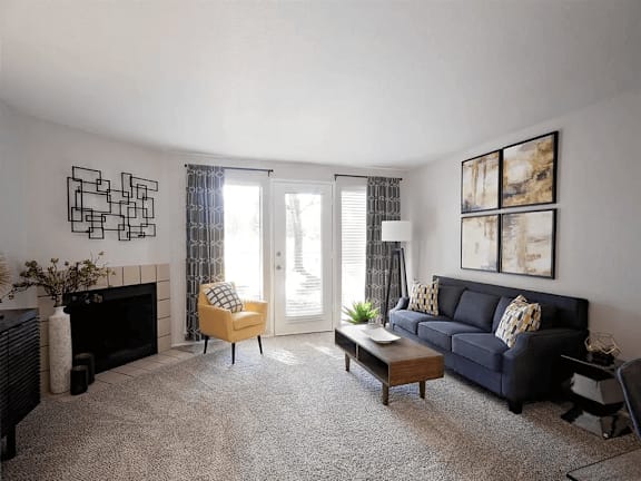 A living room with a fireplace, a yellow chair, a coffee table, a couch, and pictures on the wall.