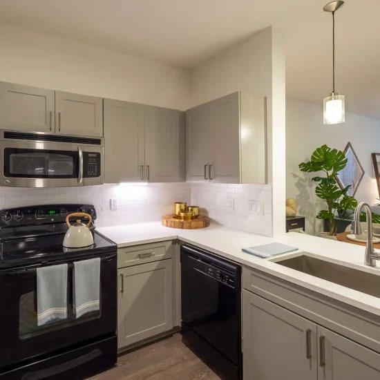 A modern kitchen with black appliances and white countertops.