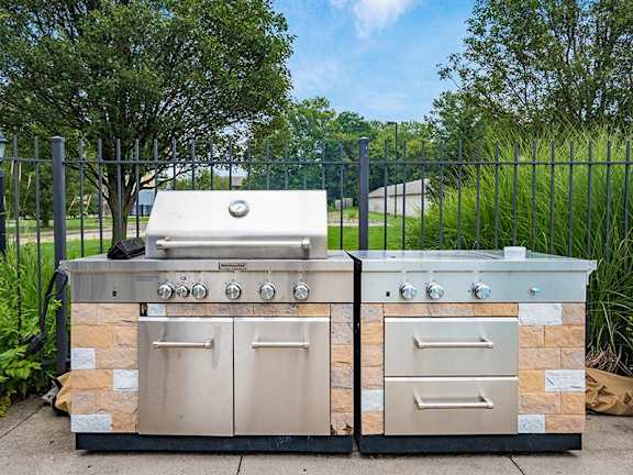 Two stone BBQs with a grill on top and a smaller one on the right.