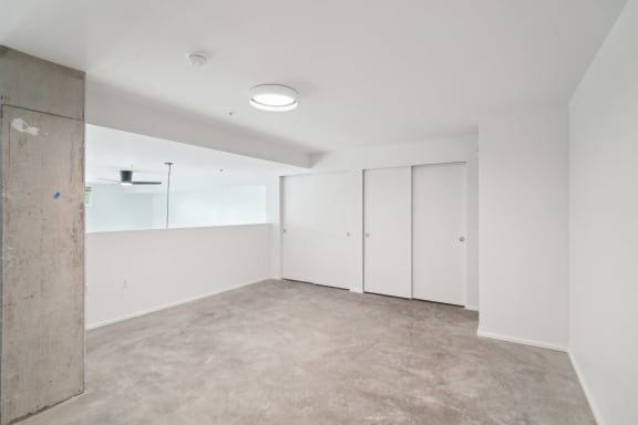 an empty living room with white walls and white closets at Analog PDX Apartments, Portland