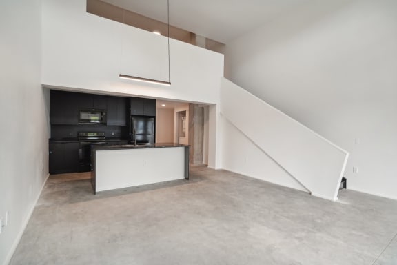 an empty living room with white walls and a kitchen at Analog PDX Apartments, Oregon