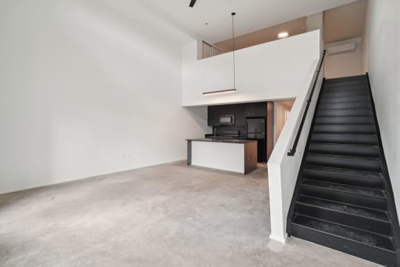 an empty room with black stairs and a white wall and a kitchen in the background at Analog PDX, Oregon