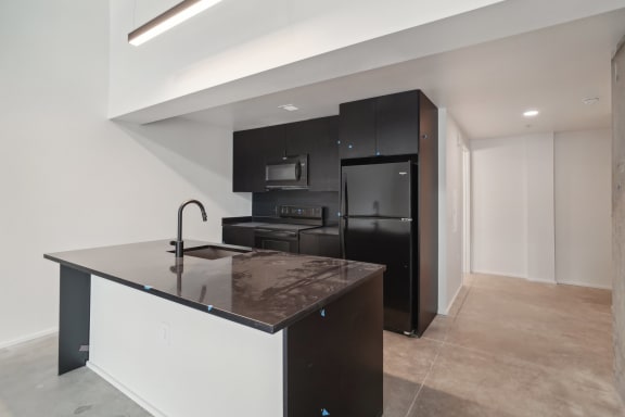 a black and white kitchen with an island and black appliances at Analog PDX Apartments, Portland, OR 97227