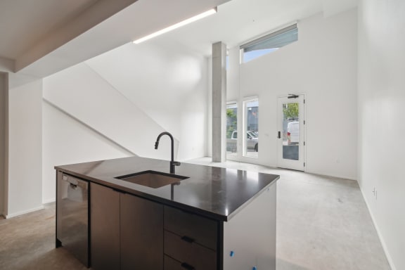 a large white kitchen with a black counter top and a sink at Analog PDX Apartments, Portland, OR