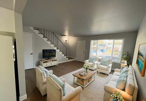 A living room with a staircase and a television.