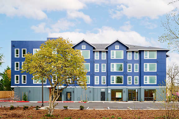A blue building with a tree in front.