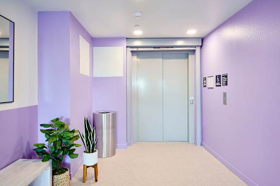 A hallway with a purple wall and a white bench.