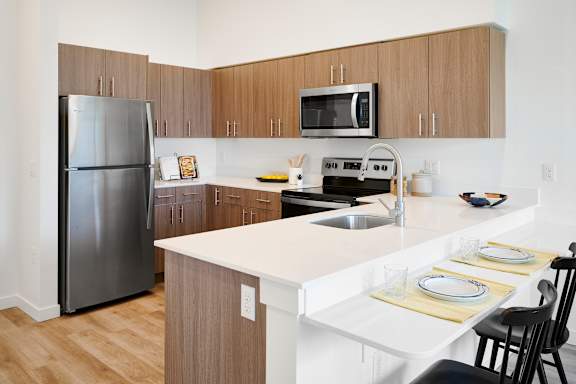 A kitchen with a refrigerator, microwave, oven, and sink.