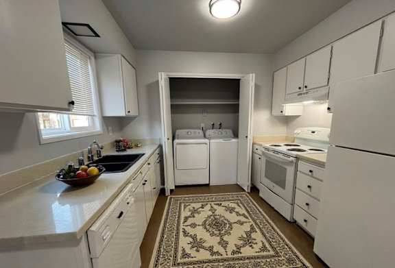 A kitchen with white appliances and cabinets.