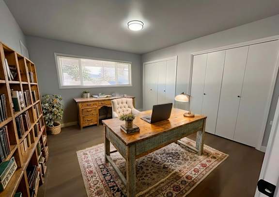 A room with a desk, laptop, and bookshelf.