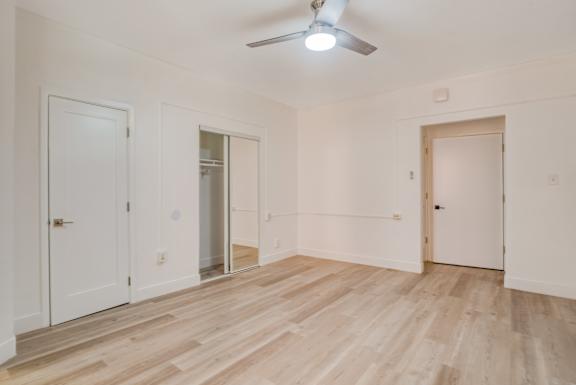 A room with wooden floors and white walls, with a ceiling fan and three doors at Clay & Tiffany, Portland, 97201