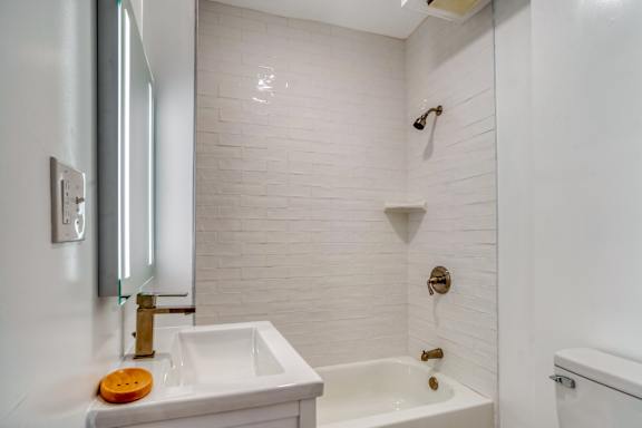 Floor Plan  A white bathroom with a sink, mirror, and bathtub.