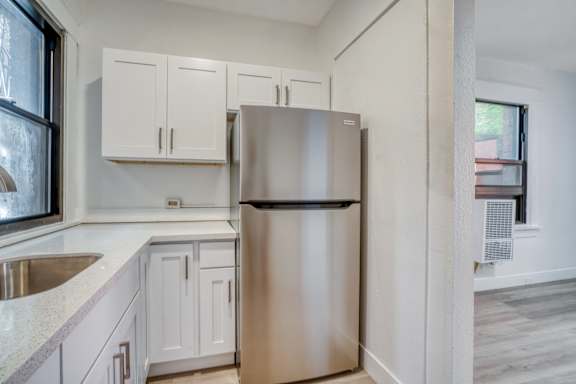 Floor Plan  A kitchen with a stainless steel refrigerator and white cabinets.