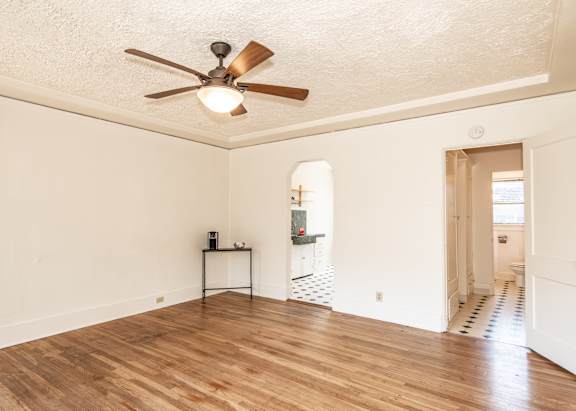 A room with a ceiling fan and wooden floors.
