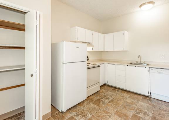 A kitchen with a white refrigerator and white cabinets.