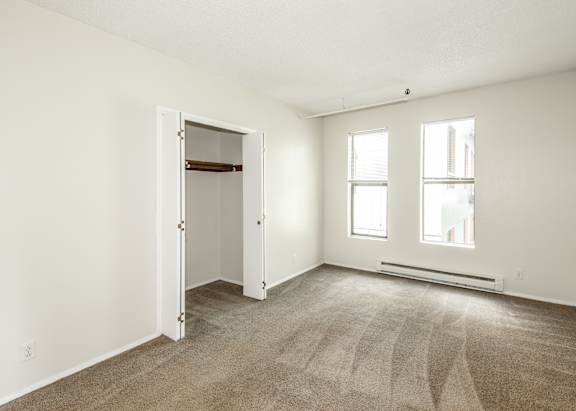 A room with a carpeted floor, two windows, and a door.