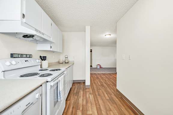 Floor Plan  A kitchen with white appliances and wooden floors.