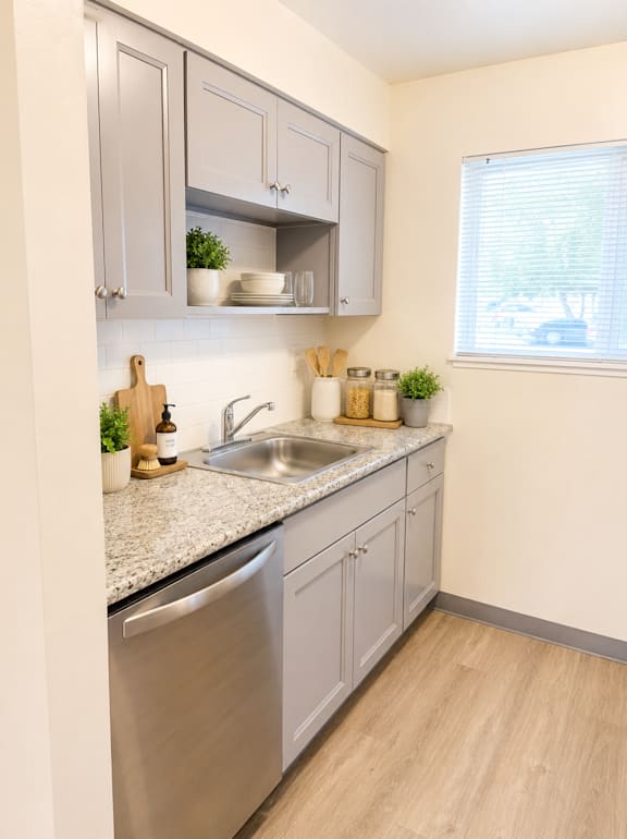 Galley kitchen with stainless steel dishwasher and granite counters at Laurel on 2nd Apartments, Newberg, Oregon