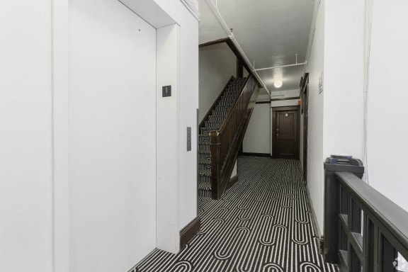 a hallway with stairs and a black and white tile floor at Clay & Tiffany, Portland, OR
