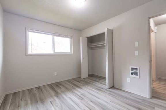 an empty room with a large window and wooden floors