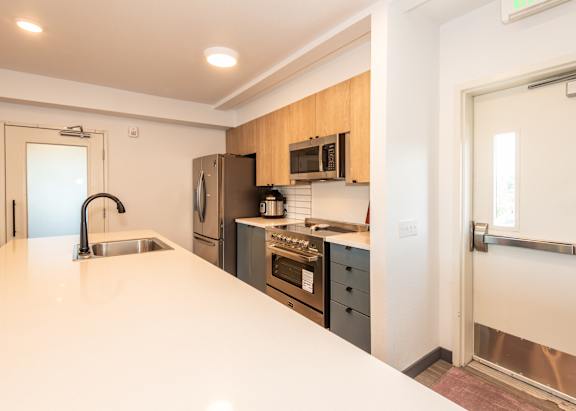 A modern kitchen with wooden cabinets and stainless steel appliances at Society 62 Apartments, Portland 97213