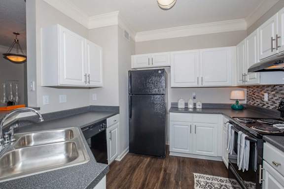 A kitchen with a black refrigerator and white cabinets.at Carrington Place at Wildewood Apartments, Columbia, SC 29223