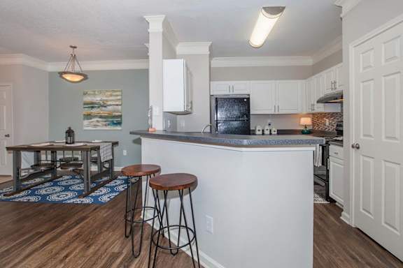 A kitchen with a white island and a black fridge.at Carrington Place at Wildewood Apartments, Columbia, SC