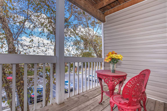 a table with a vase of flowers and two chairs on a deck with a view of