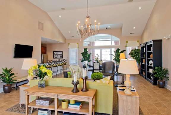 A well-lit living room with a large chandelier and a green sofa.