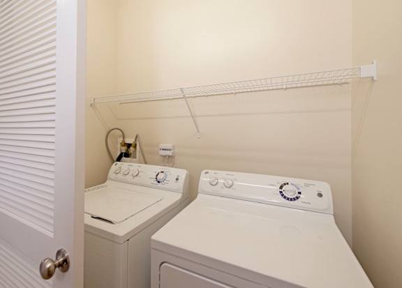 Two white front load washing machines in a small laundry room.