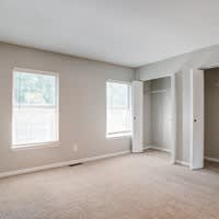A room with a carpeted floor and two windows.