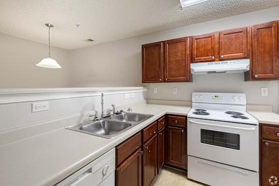 A kitchen with white appliances and wooden cabinets at Cross Creek Apartments, Beaufort, SC, 29906