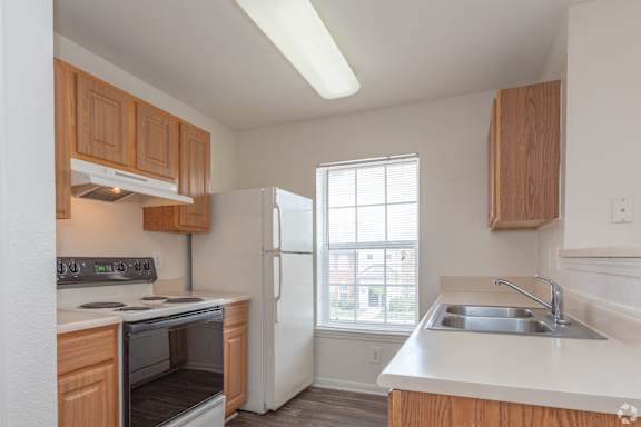 A kitchen with wooden cabinets and a white refrigerator at The Regency Apartment Homes, Manassas, VA