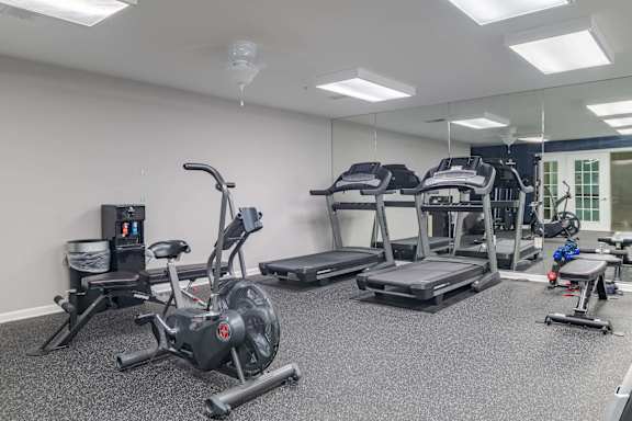 A gym with a variety of equipment including treadmills, stationary bikes, and weight machines at Kendrick Court, Herndon, 20171