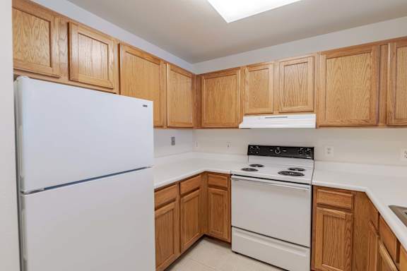 A kitchen with wooden cabinets and white appliances at Kendrick Court, Herndon, 20171