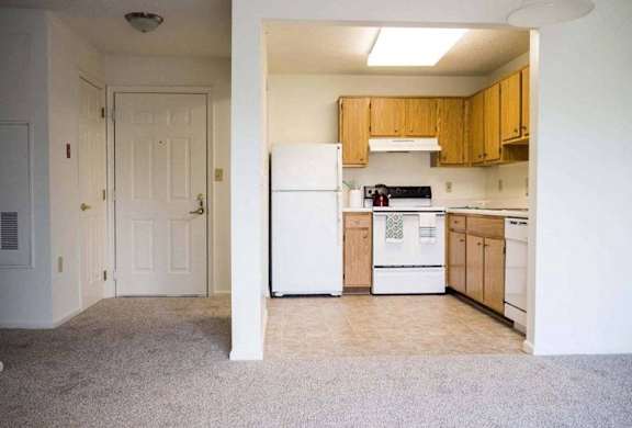 A kitchen with white appliances and wooden cabinets at Greenbrier Seniors Apartments, Chesapeake, Virginia