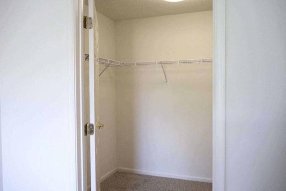 A white closet with a door and a hanger rod at Greenbrier Seniors Apartments, Chesapeake, Virginia