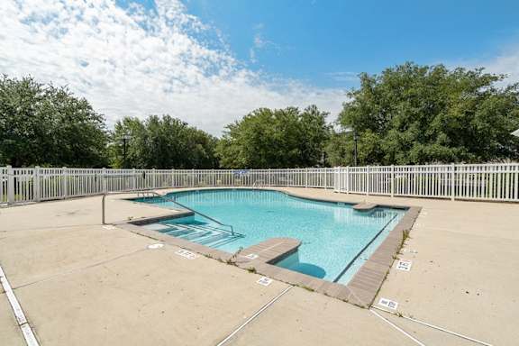 A large outdoor swimming pool surrounded by a fence at Palms on Ashley River Apartments, Ladson
