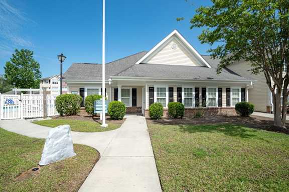 A house with a white picket fence in front at Palms on Ashley River Apartments, Ladson