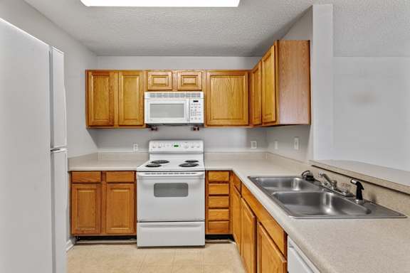 A kitchen with wooden cabinets and white appliances at Palms on Ashley River Apartments, Ladson