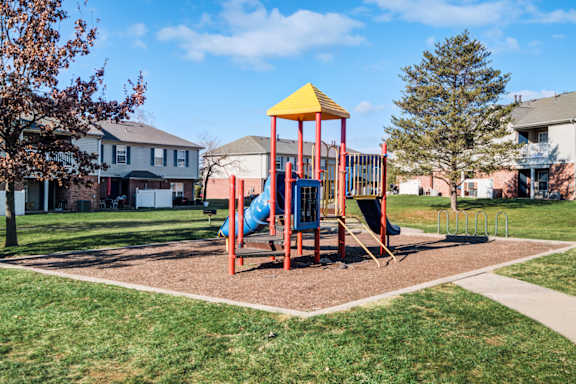 A playground with a yellow and red structure and a blue slide at The Regency Apartment Homes, Manassas, VA