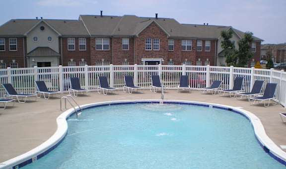 A pool surrounded by white chairs and a white fence at The Regency Apartment Homes, Manassas, VA