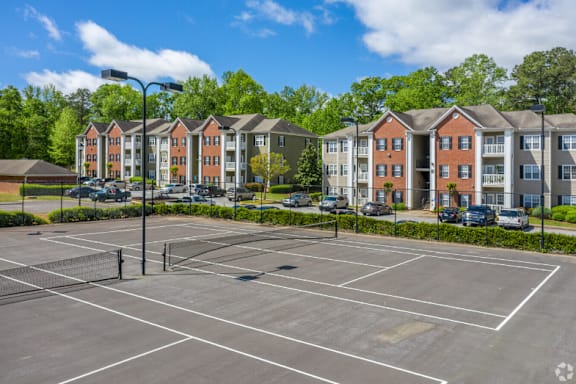 an empty tennis court with apartments in the background  at Magnolia Lake Apartments, Carrollton