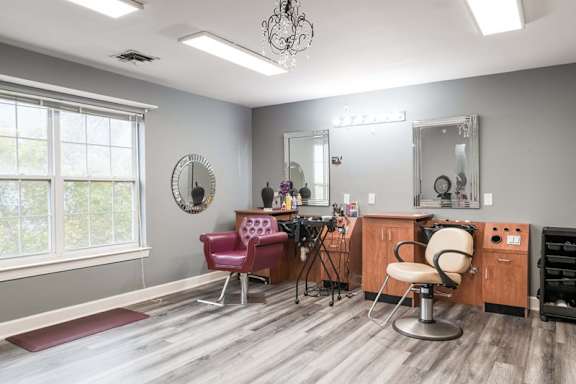 A salon with a red chair and a mirror.